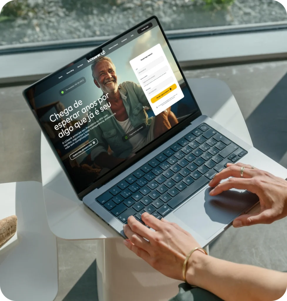 Laptop aberto exibindo o site do LCbank com o título "Chega de esperar por algo que já é seu